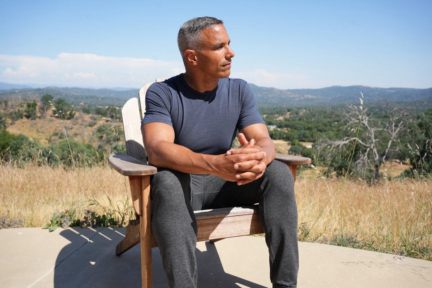 Jay Williams sitting in a wooden chair on a hilltop in California